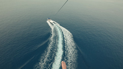 Parasailing above the expansive blue ocean water with a boat below