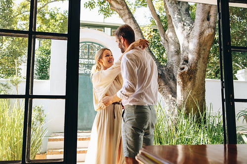 Carefree couple smiling at each other outside a hotel entrance