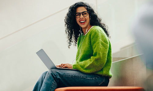 Woman student smiles with a laptop in the library during online research