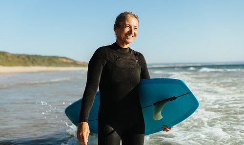 Senior woman enjoying surfing at the beach during a sunny day