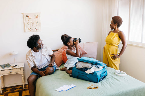 Family fun on a vacation: Parents and daughter capturing happy moments in a bedroom
