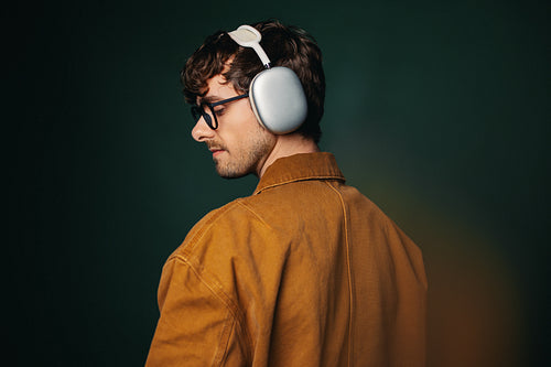 Man wearing headphones in studio portrait with glasses and side profile