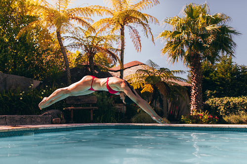 Woman in bikini diving into swimming pool