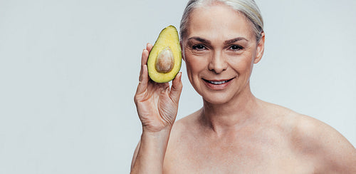 Elderly woman showing an avocado