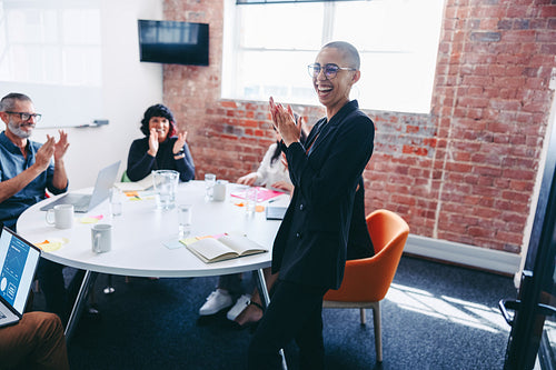 Young businesswoman being applauded by her team in an office