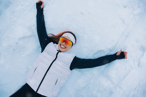 Female athlete resting playfully in snow after winter training session