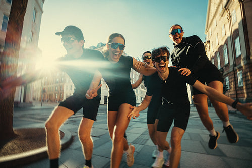 Running friends socializing outdoors after group fitness in a sunny city street