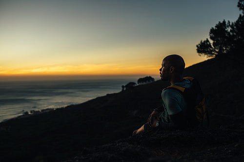 Sportsman resting by mountain trail at sunset