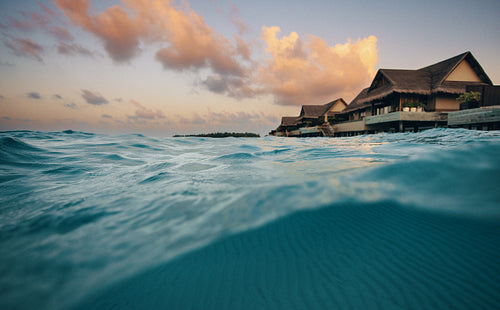 Scenic overwater resort villa with waves at sunset
