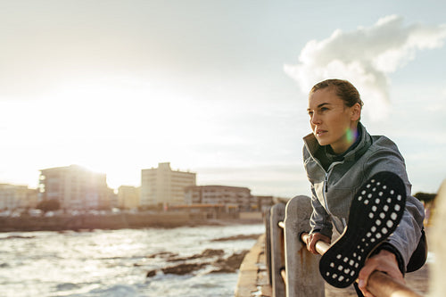 Fitness woman stretching at seaside promenade