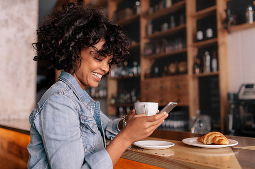 Smiling woman using smart phone in a modern cafe