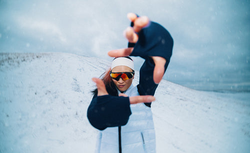 Training outdoors, the woman holds a playful pose in winter snow during her workout