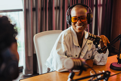 Young woman recording a podcast in studio with professional microphone and headphones