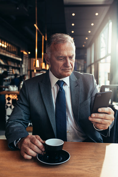 Senior entrepreneur at cafe texting on smartphone