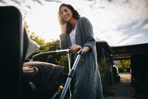 Woman talking on the phone and pushing baby stroller