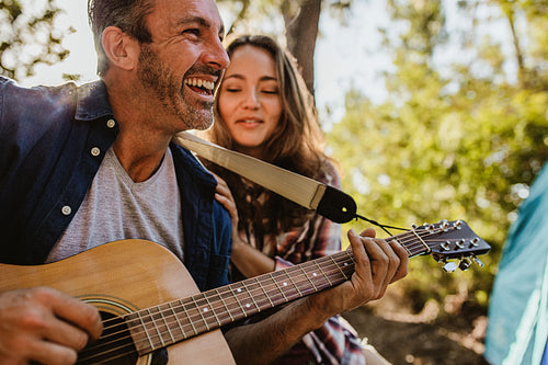 Man playing music with girlfriend at campsite