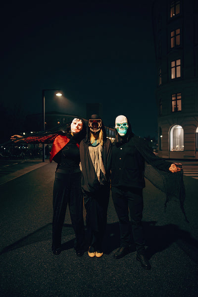 Three friends in creative costumes enjoying Halloween night in an urban setting