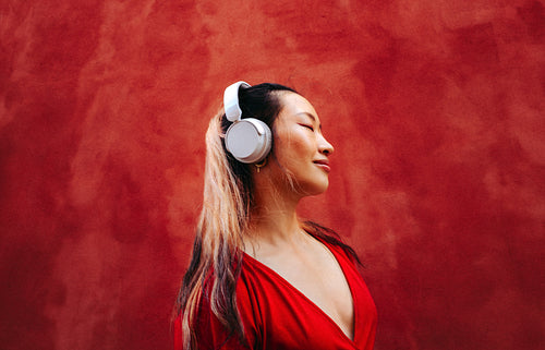 Woman listens to music on headphones with eyes closed in close up