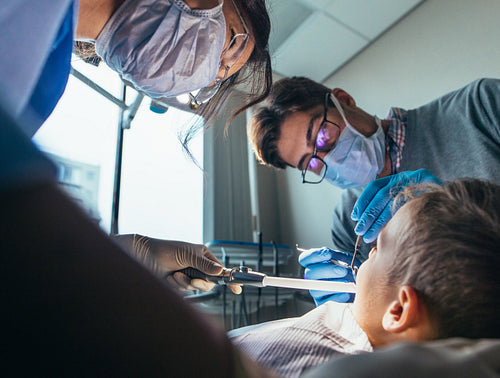 Pediatric dentist doing dental treatment on little boy