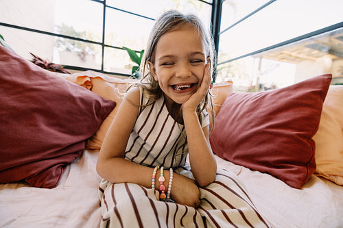 Girl smiling on couch with colorful pillows