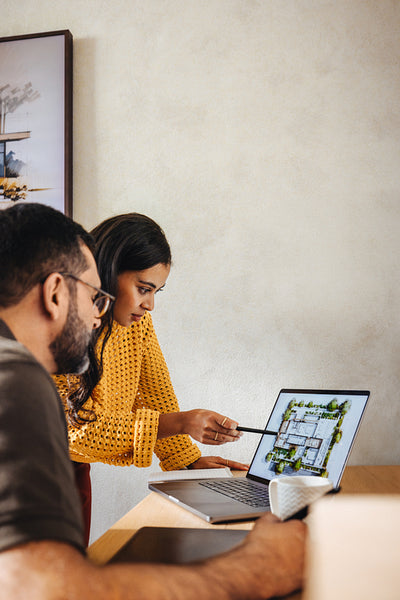 Young architects discussing floor plan designs on a laptop at their workspace