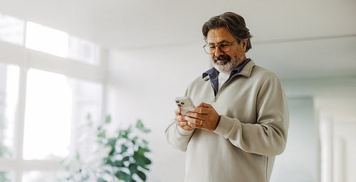 Senior man uses a smartphone at home