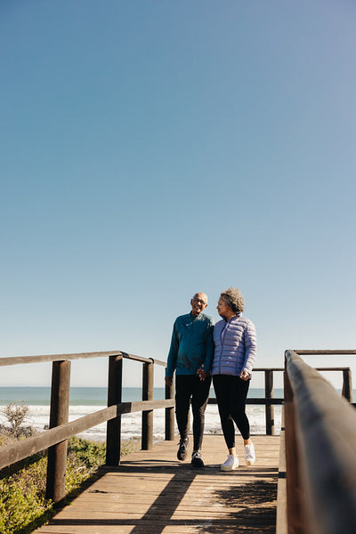 Romantic senior couple taking a walk on a bridge at the beach
