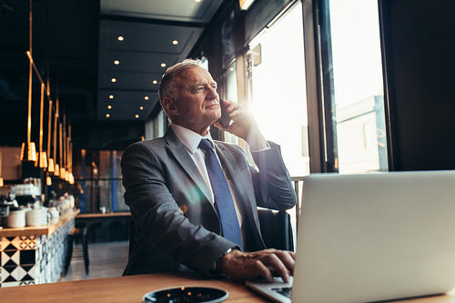 Senior businessman at coffee shop making a phone call.