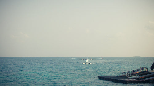 Seaplane arriving on the turquoise ocean near a beautiful tropical island resort in the morning