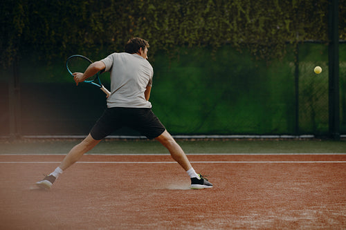 Tennis player sliding for a backhand shot