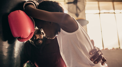 Close up of a tired boxing kid with his coach