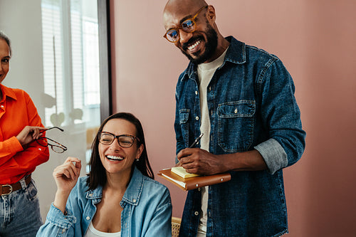 Happy employees collaborating in modern colorful office while writing notes