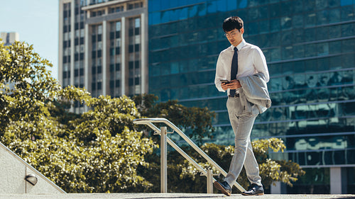 Businessman walking and using a smart phone outdoor