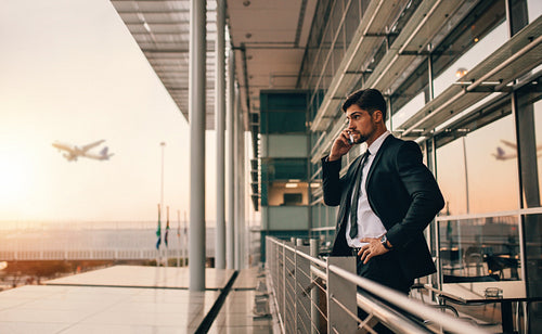 Businessman on airport lounge balcony making phone call