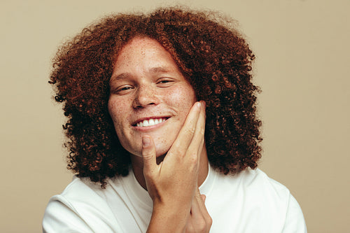 Man with ginger hair touching and feeling his freckled, moisturized face