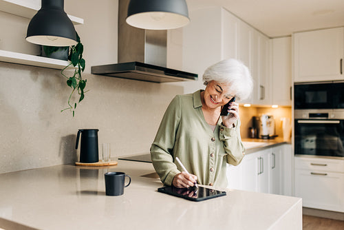 Mature businesswoman taking a phone call at home