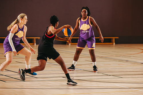 Female basketball players competing in a dynamic game on an indoor court