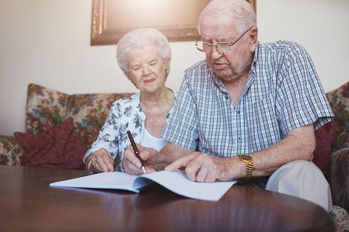 Senior couple at home signing paperwork together