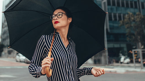 Business woman on city street with umbrella