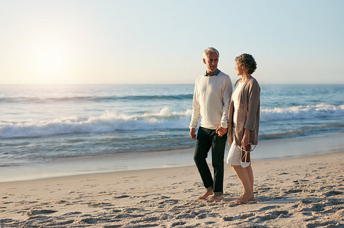 Loving senior couple walking along the beach in evening