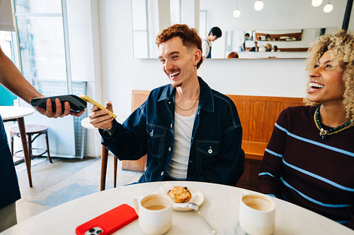 Friends making a contactless payment at a cafe