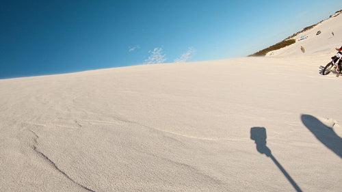 Cross country athlete riding his dirt bike over sand dunes