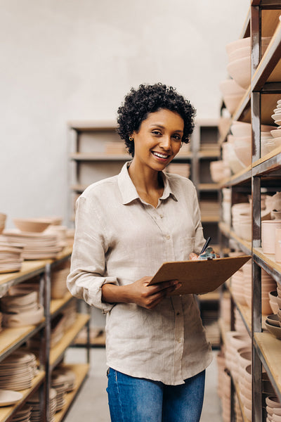 Cheerful young ceramist smiling at the camera in her store
