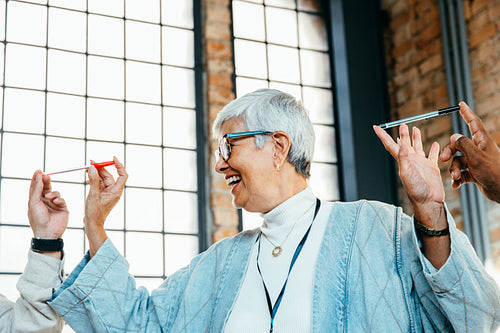 Senior businesswoman in professional setting shares a joyful moment while collaborating with colleagues in a modern office environment