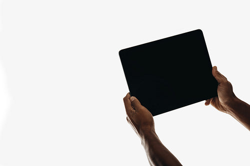 Hands holding a tablet with a blank screen on a plain white background