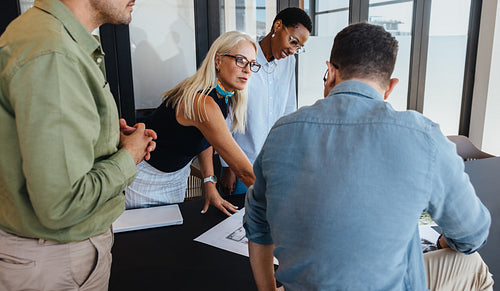 Office team discussing a project together around a desk during a meeting