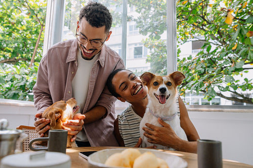 Brazilian couple smiling with rescue dogs at breakfast table with pão de queijo