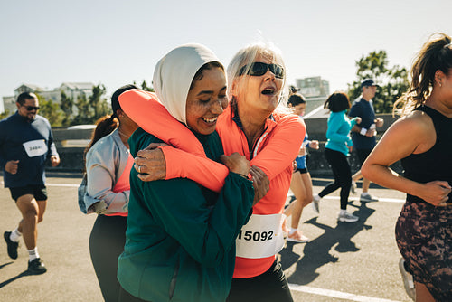 Joyful friends running together showcasing age contrast in a marathon