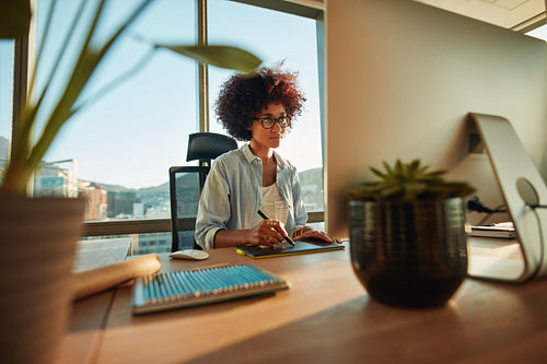 Young female designer using graphics tablet while working with computer