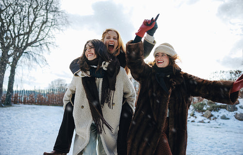 Woman and friends enjoy a piggyback ride in the snowy park